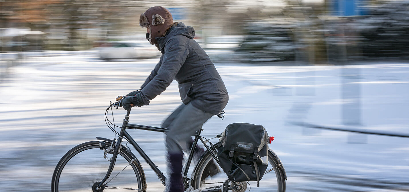 Radfahren kann auch im Winter Spaß machen. Mann fährt auf ungeräumten Radweg im Winter